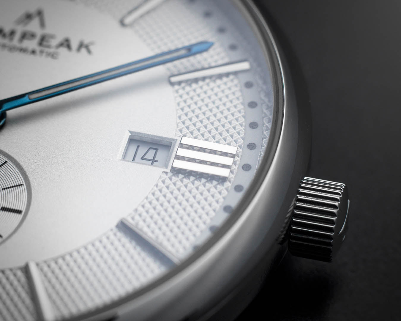 Detailed view of the Mallory Timeless White watch dial, showing the date window, heat-blued hands, applied indices, textured finish, and signed crown.