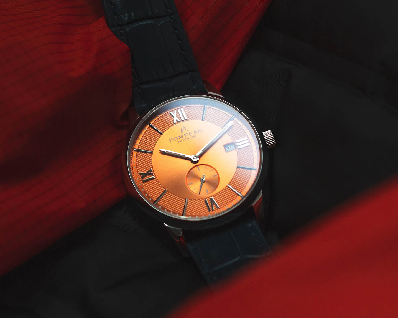 Mallory Orange Crush Swiss automatic watch on a blue mock crocodile leather strap, pairing bold colour with timeless craftsmanship.