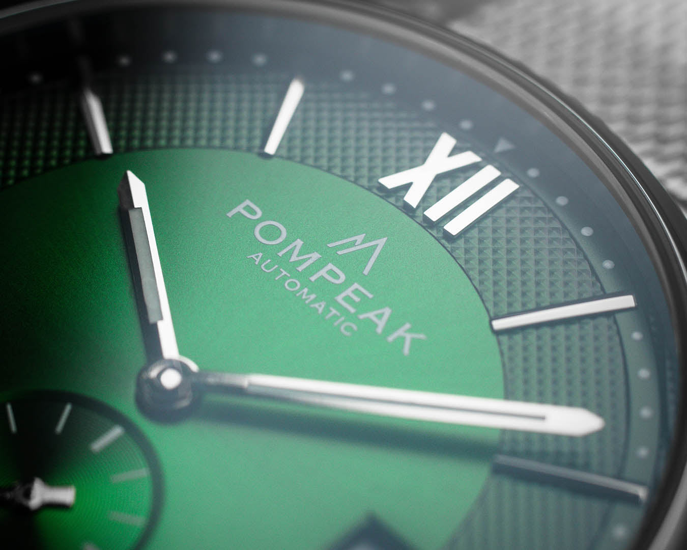 Close-up of the Mallory British Racing Green watch dial, showcasing the printed logo, polished silver hands, applied Roman numerals, and a textured fumé finish.