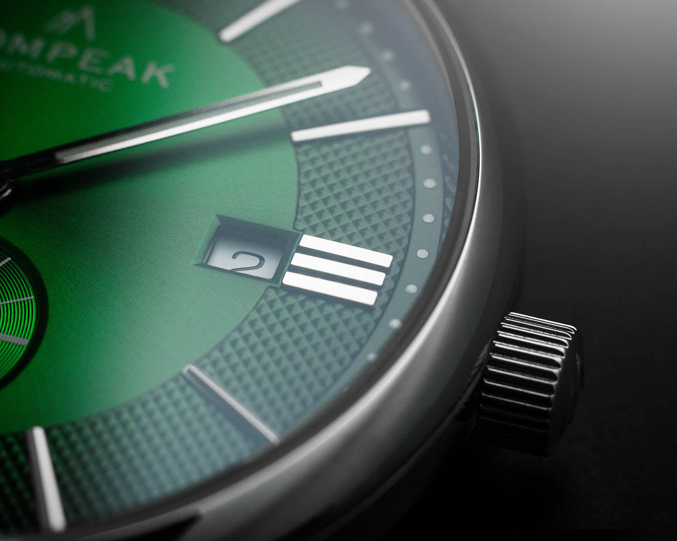 Detailed view of the Mallory British Racing Green watch dial with a date window, polished silver hands, applied indices, textured fumé finish, and a signed crown.
