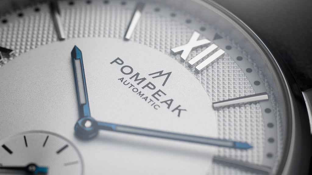 Macro image of the Pompeak Mallory displaying the applied Roman numerals and textured white dial with heat blued hands