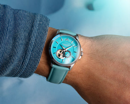 Blue watch with a guilloche dial on a wrist against a blue background