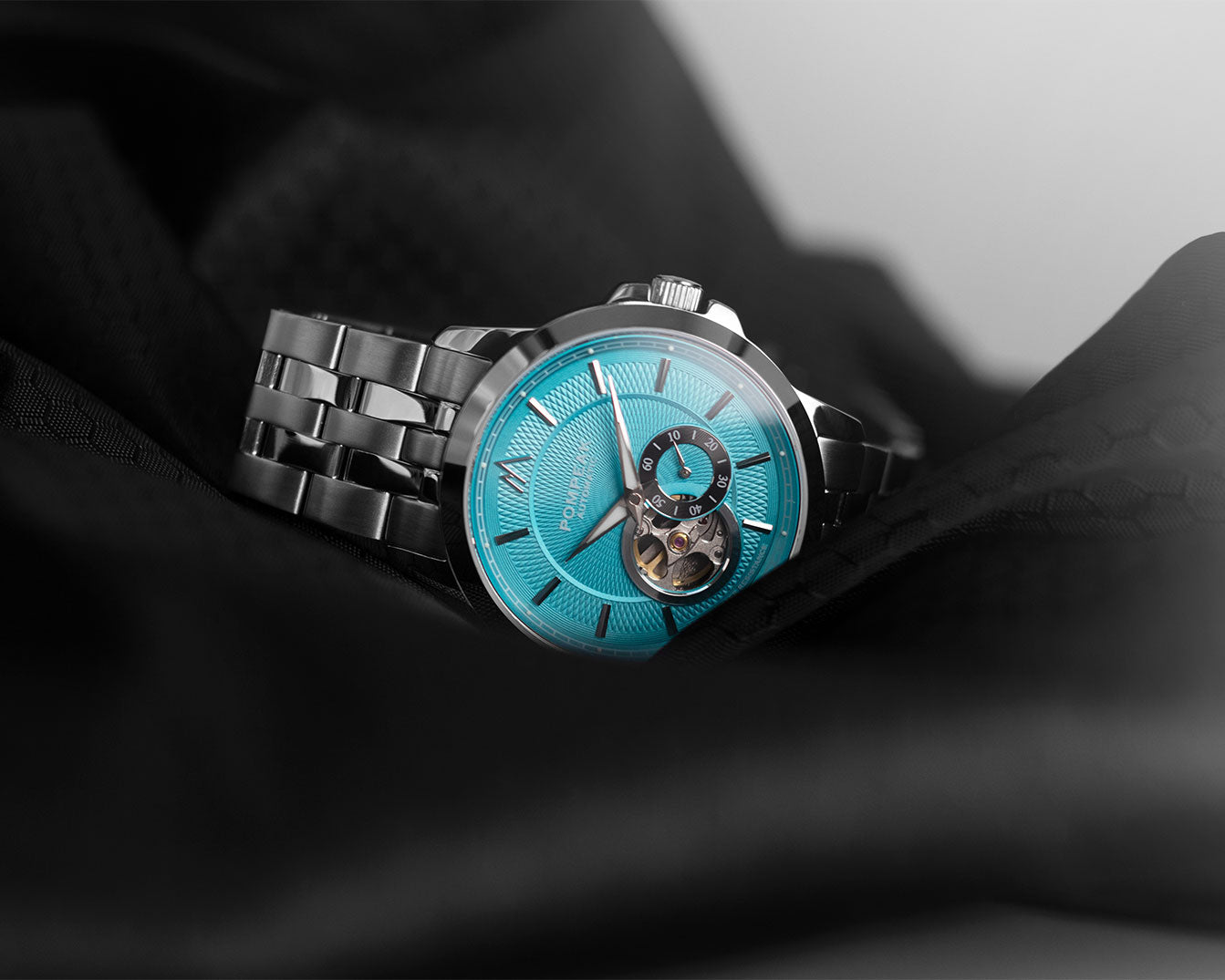 Open Heart watch with blue face and silver metal strap on a dark fabric background