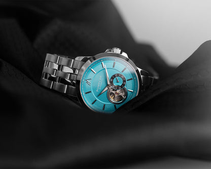 Open Heart watch with blue face and silver metal strap on a dark fabric background