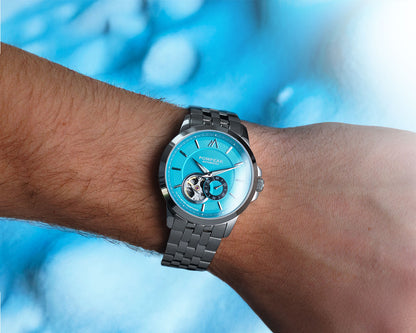 Blue watch with a stainless steel bracelet on a wrist against a blue background